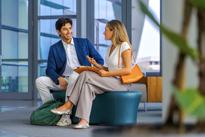 Man and woman sitting on a bench at the student center on campus